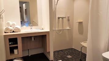 Un baño moderno con lavamanos, espejo, toallero, ducha e inodoro.