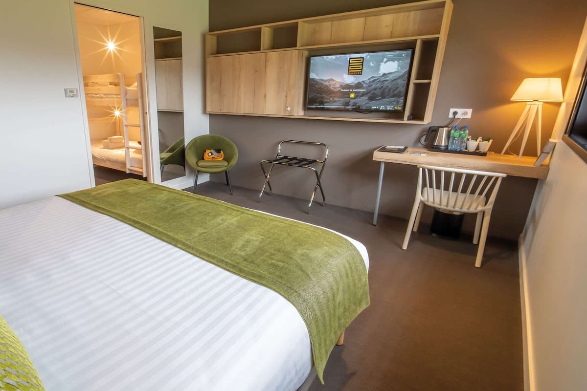 Een hotelkamer met een bed, bureau, stoel, televisie en kledingkast.