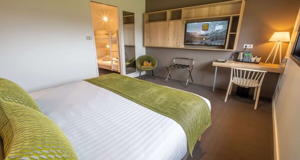 Una habitación de hotel con cama, escritorio, silla, televisor y armario.