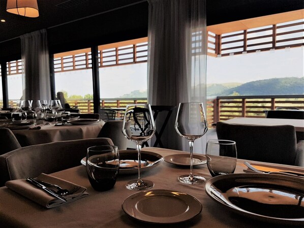 A restaurant with tables set for dining, large windows, and a view of the outdoors. - Mildiss Hotel Spa & Restaurant, BW Signature Collection (Besse-et-Saint-Anastaise)