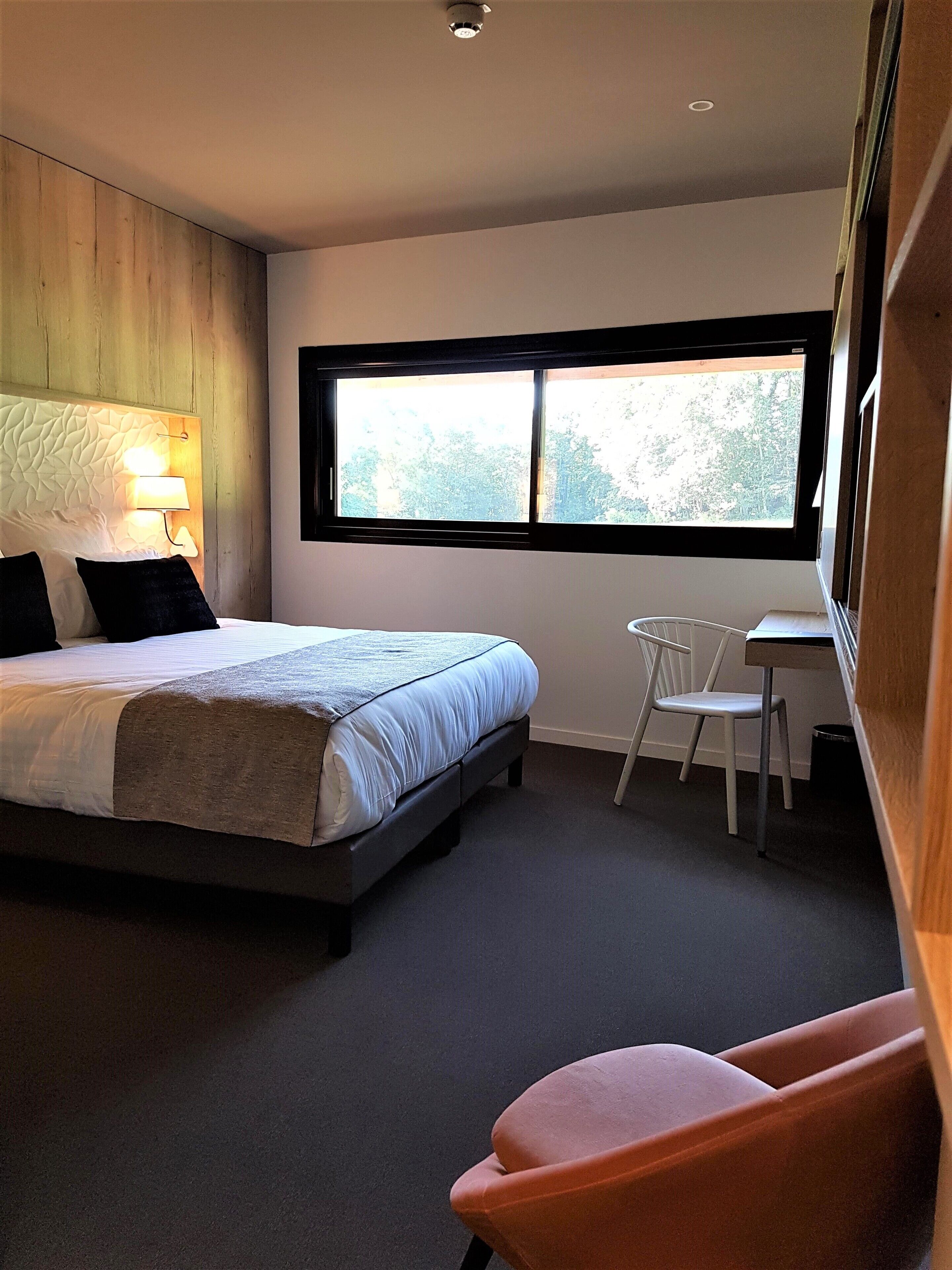 A bedroom with a bed, a desk, and a chair.