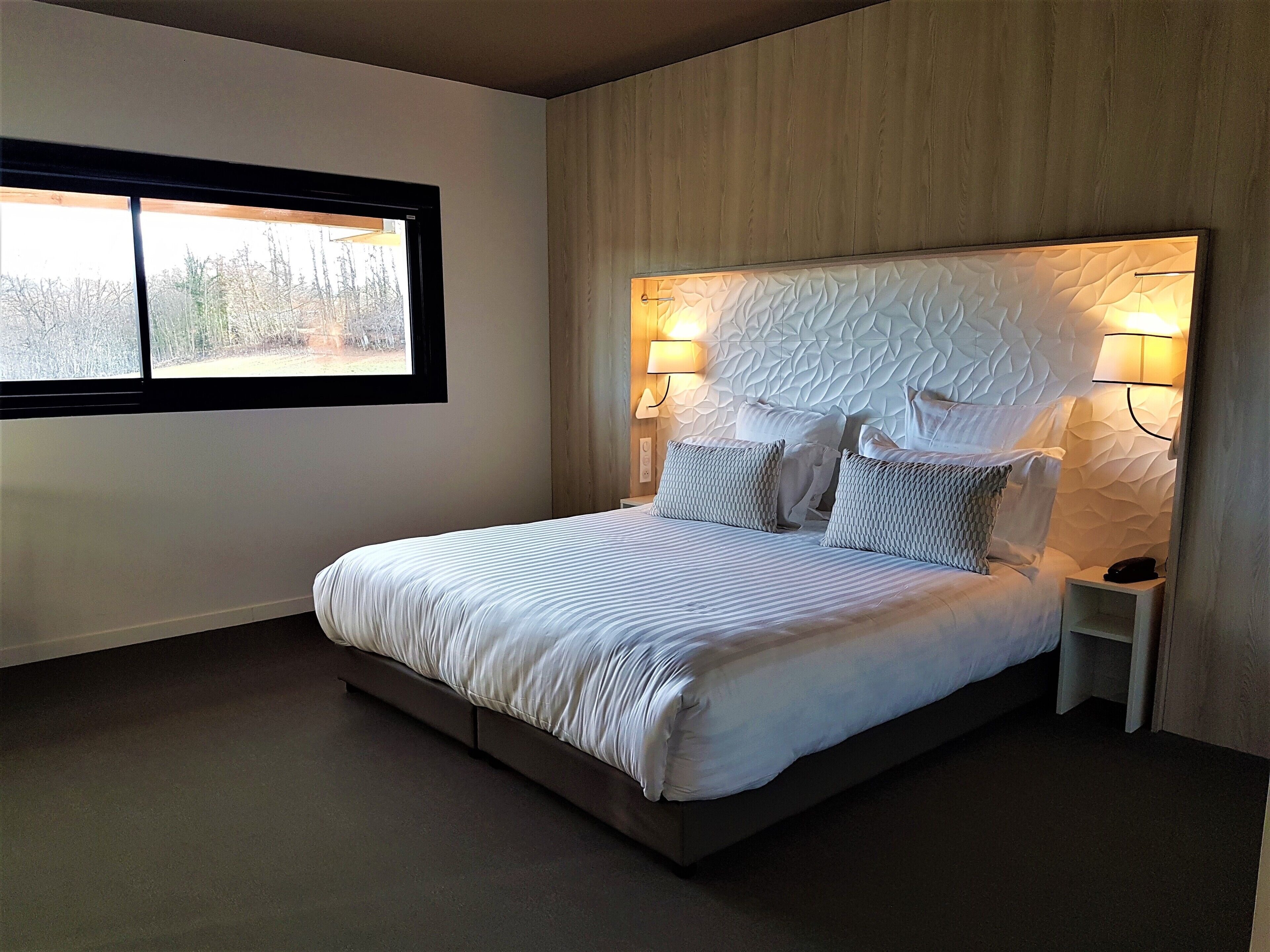 Una camera da letto moderna con un letto grande, due comodini e una testiera dalla texture particolare.
