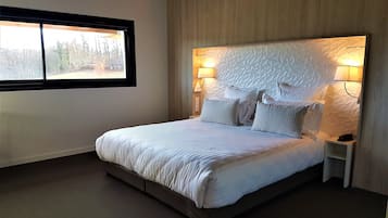 Una camera da letto moderna con un letto grande, due comodini e una testiera dalla texture particolare.
