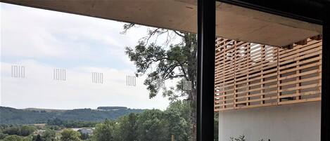 Una terraza con dos sillas, vista a un paisaje rural y una estructura de celosía de madera.