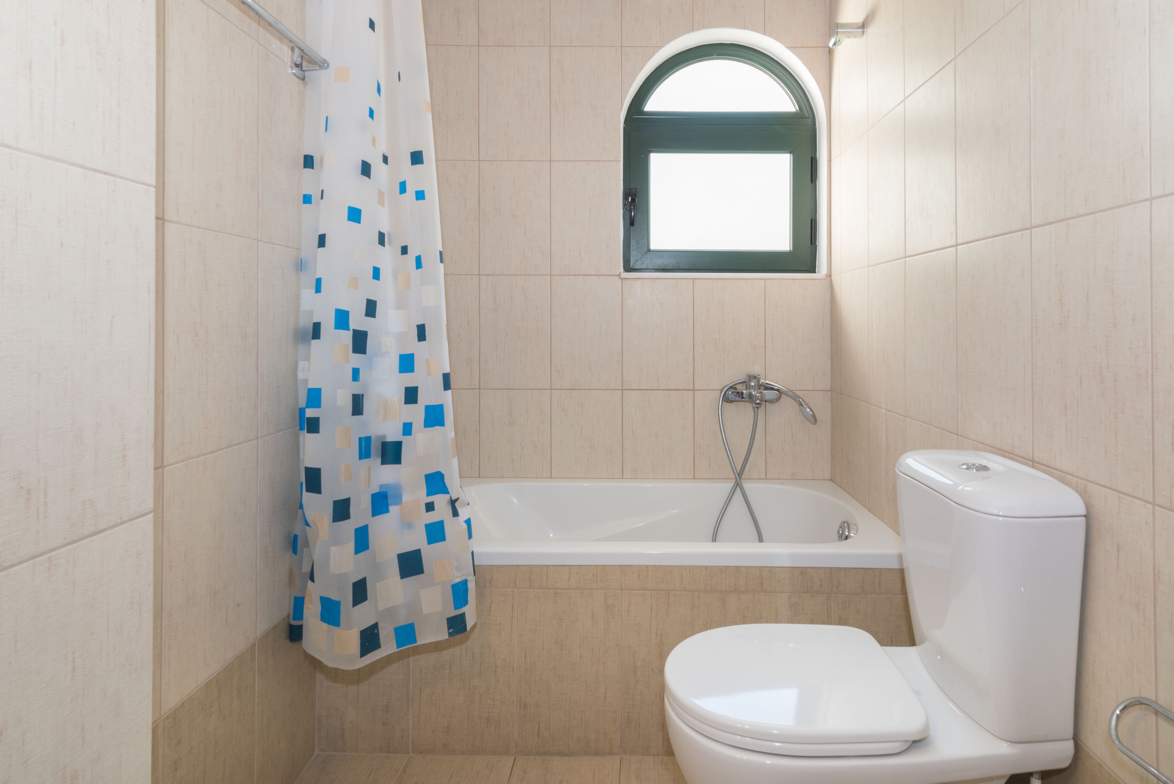 A bathroom with a bathtub, toilet, and a window above the toilet.