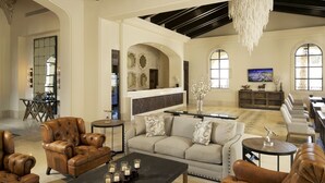 A spacious living room with leather armchairs, a sofa, and a coffee table with candles. There is a fireplace, a television, and a chandelier. - Grand Solmar at Rancho San Lucas (Cabo San Lucas, Baja California Sur)