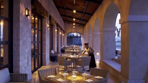 A restaurant with outdoor seating, tables set with white tablecloths, and a waiter attending to a table. - Grand Solmar at Rancho San Lucas (Cabo San Lucas, Baja California Sur)