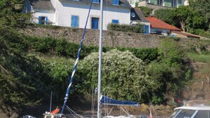 A coastal scene with a lighthouse, a white building with green shutters, and boats docked near the shore. - 7 Gîtes in 100 acres with heated pool. Near Pont Aven, Concarneau, beaches 15km (Bretagne)