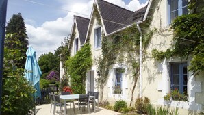 A two-story house with a patio, a table with chairs, and a blue umbrella. - 7 Gîtes in 100 acres with heated pool. Near Pont Aven, Concarneau, beaches 15km (Bretagne)