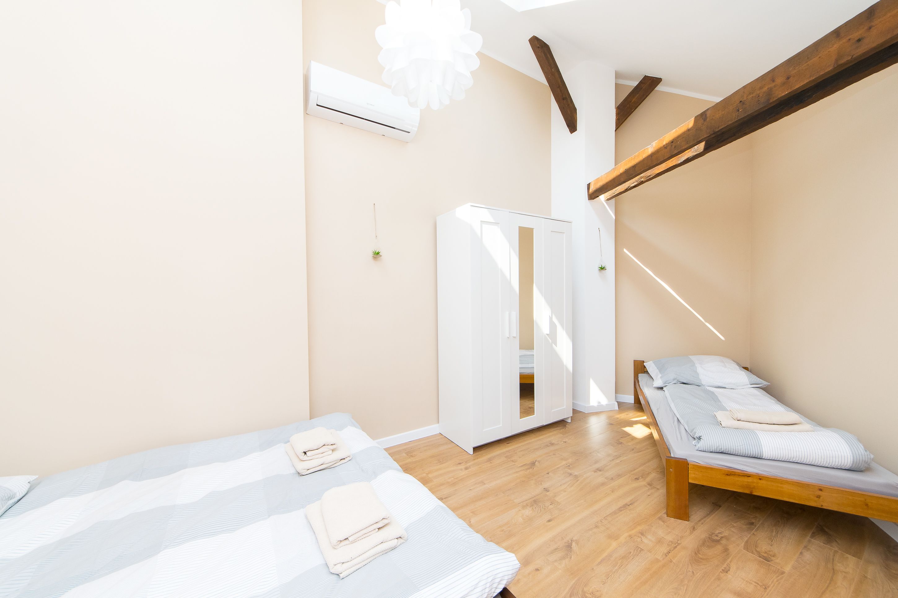 Ein Schlafzimmer mit zwei Betten, Holzbalken, einer Klimaanlage und einer Tür zu einem anderen Raum.