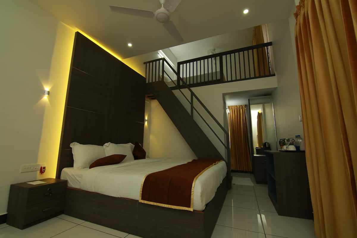 A modern bedroom with a large bed, a nightstand, a desk, and a staircase to an upper level.