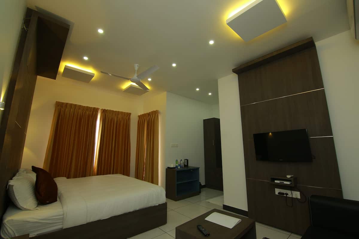 A hotel room with a bed, a desk, a TV mounted on the wall, and a ceiling fan.