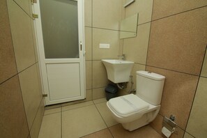 Un baño pequeño con inodoro, lavamanos y espejo.