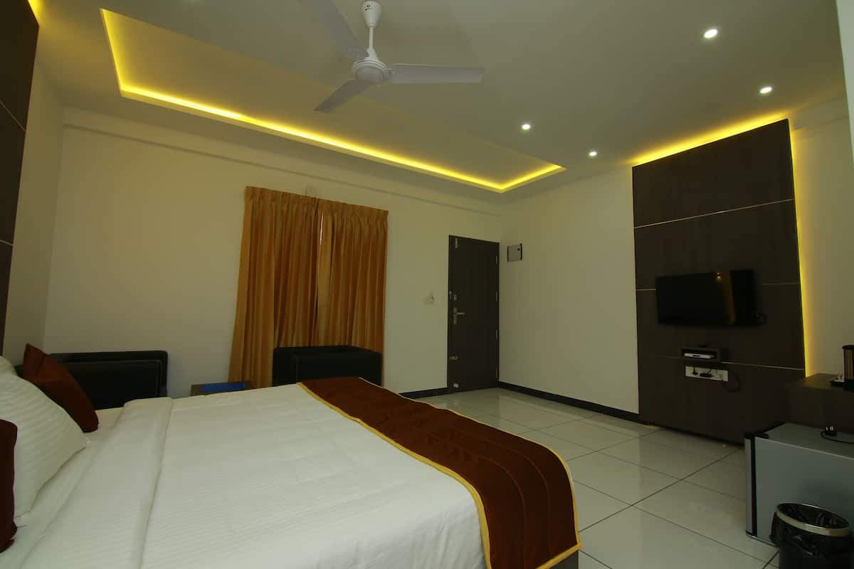 A hotel room with a bed, a ceiling fan, a TV, and a desk.
