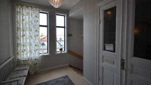 A hotel room with a large window, a bench, a rug, and a door with a nameplate. - Hotell Royal (Harnosand)
