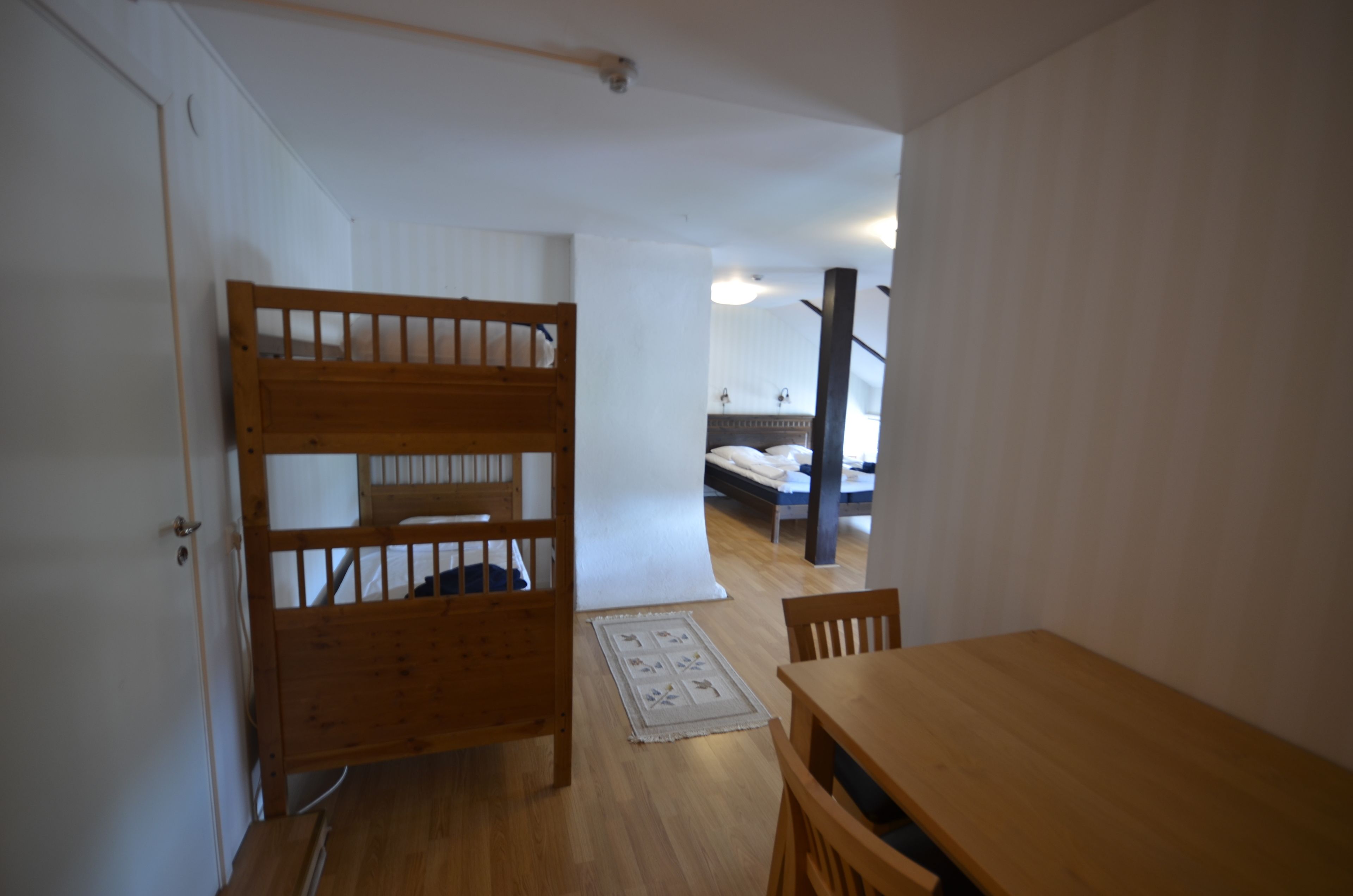 Una habitación con una cama nido de madera, una mesa de madera y una silla.