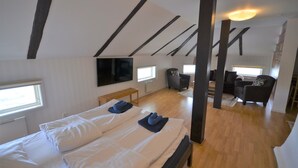 A room with two beds, a TV, a sofa, and a staircase. - Hotell Royal (Harnosand)