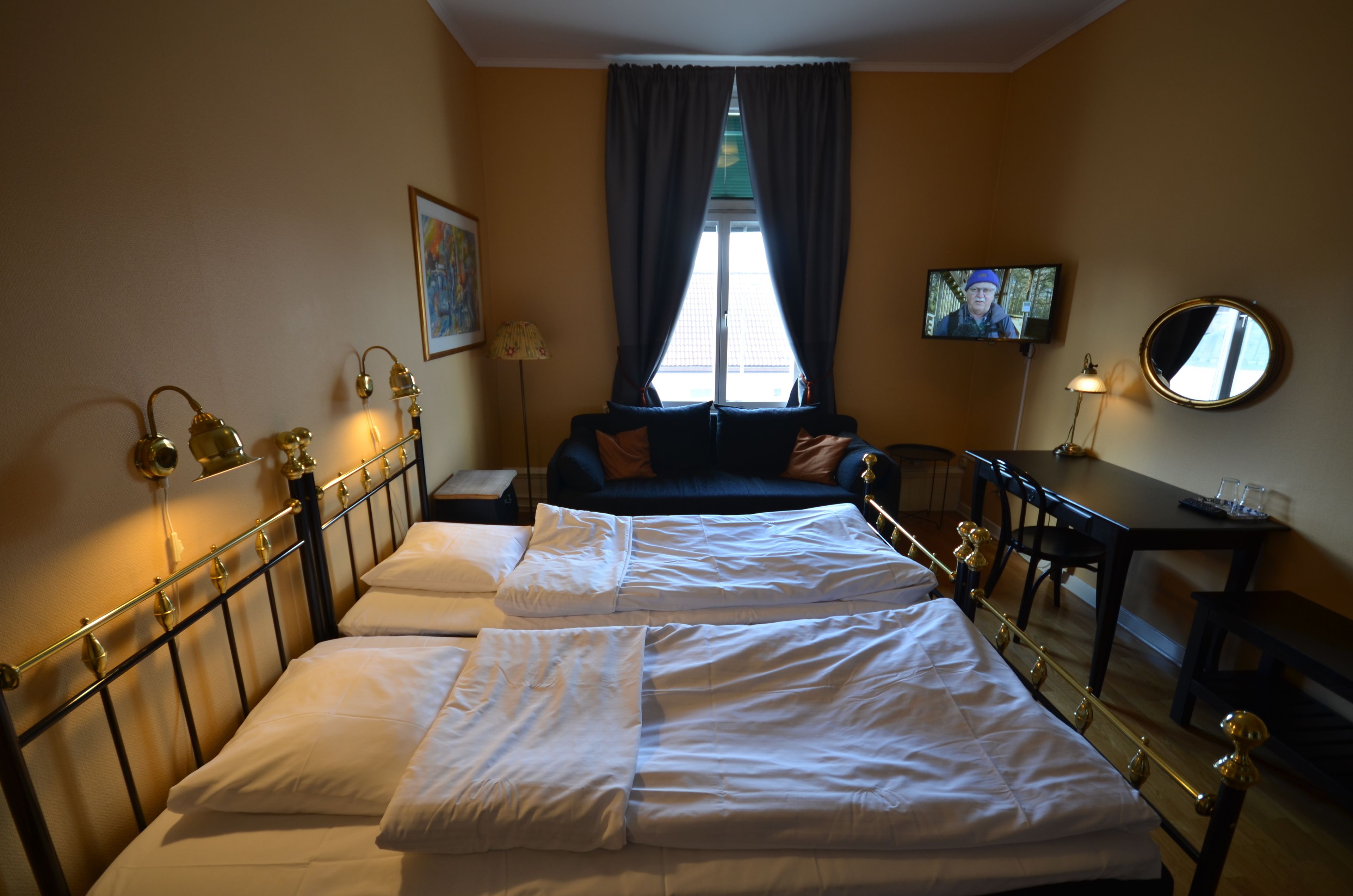 Een hotelkamer met een bed, een bureau, een stoel, een televisie en een raam met gordijnen.