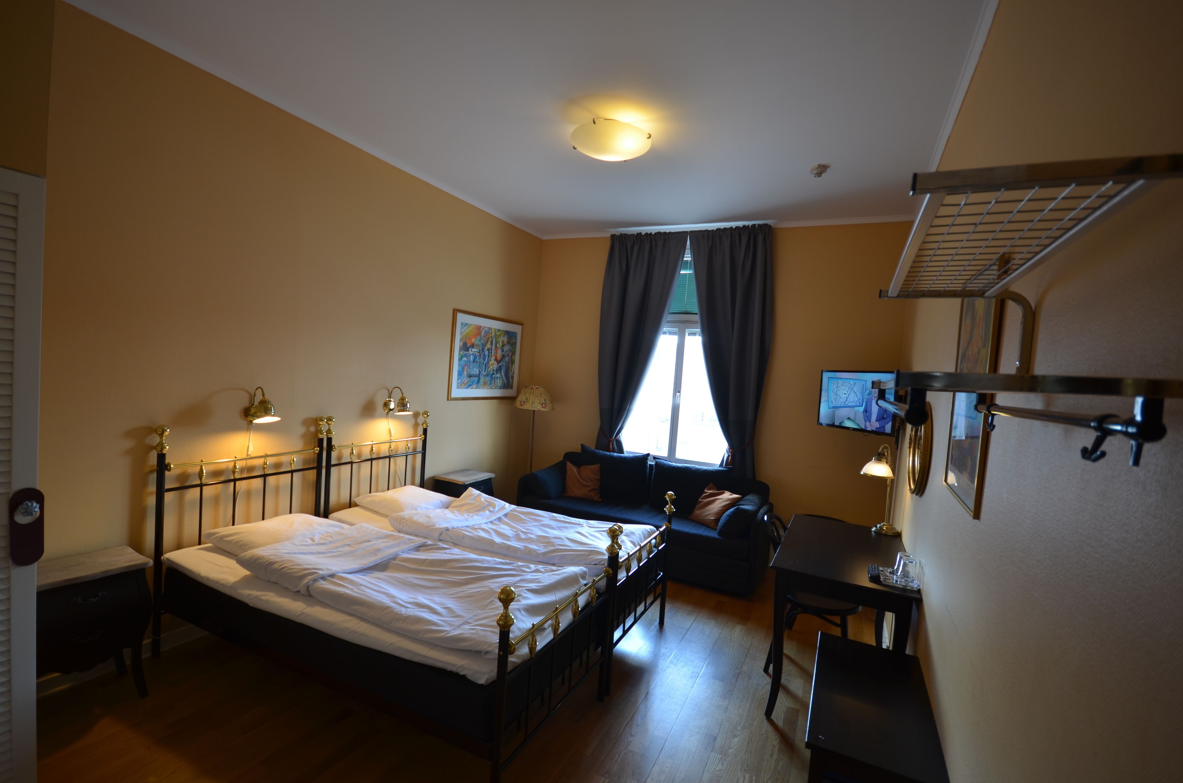 A bedroom with a bed, a desk, a chair, a sofa, and a television.