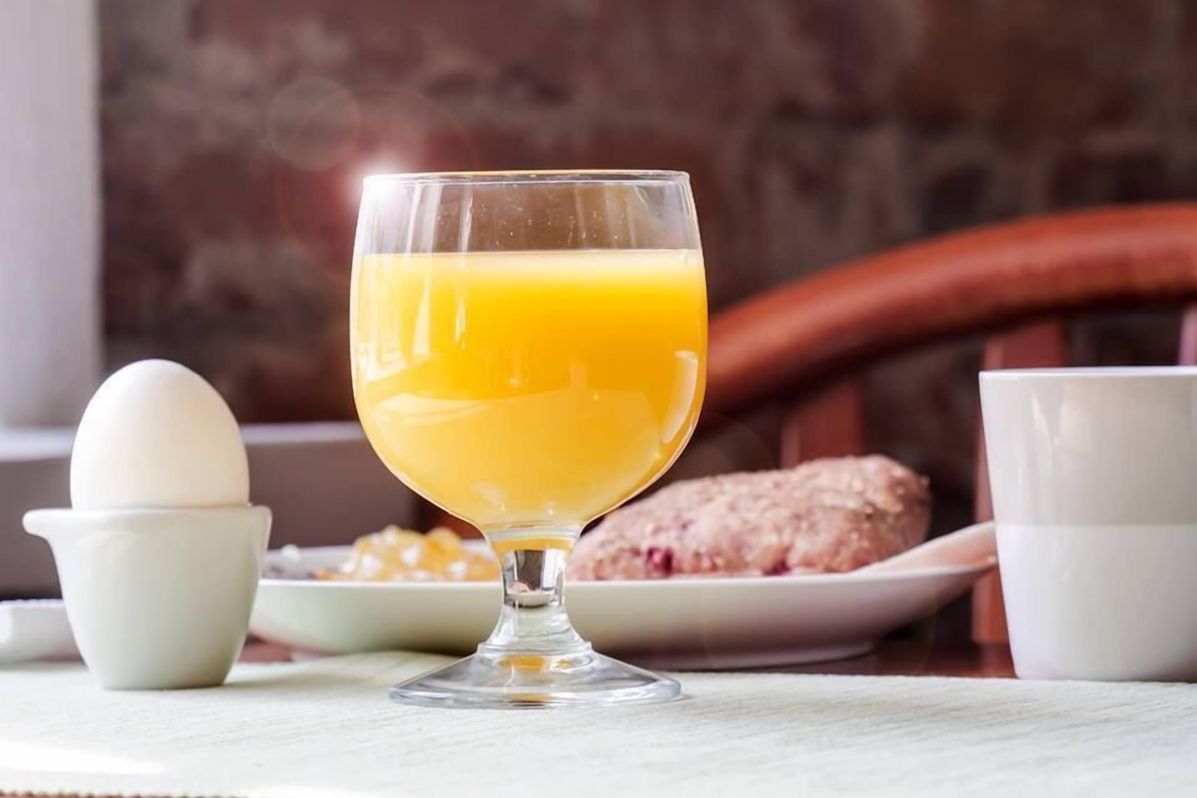 Desayuno con un vaso de jugo de naranja, un huevo blanco y un plato de comida.