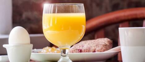 Desayuno con un vaso de jugo de naranja, un huevo blanco y un plato de comida.