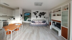 A modern kitchen with white cabinets, a dining table with chairs, a sofa, and a world map mural on the wall. - Sofia and Oscar's house Lake Como Canzo (Canzo)