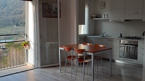 A modern kitchen with a dining area, large windows, and a balcony with a view of a mountainous landscape. - Sofia and Oscar's house Lake Como Canzo (Canzo)
