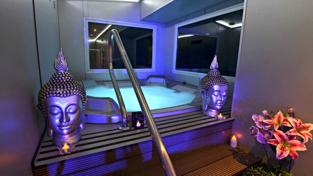 A room with a wooden platform, two Buddha statues, a small candle, and a flower arrangement. - Serra de Prades Resort - Campsite (Vilanova de Prades)
