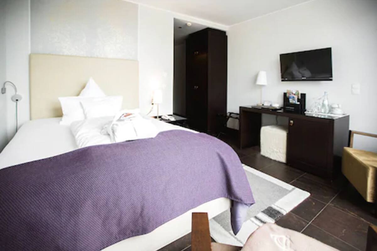 Een hotelkamer met een bed, een bureau, een stoel, een televisie en een badkamers deur.