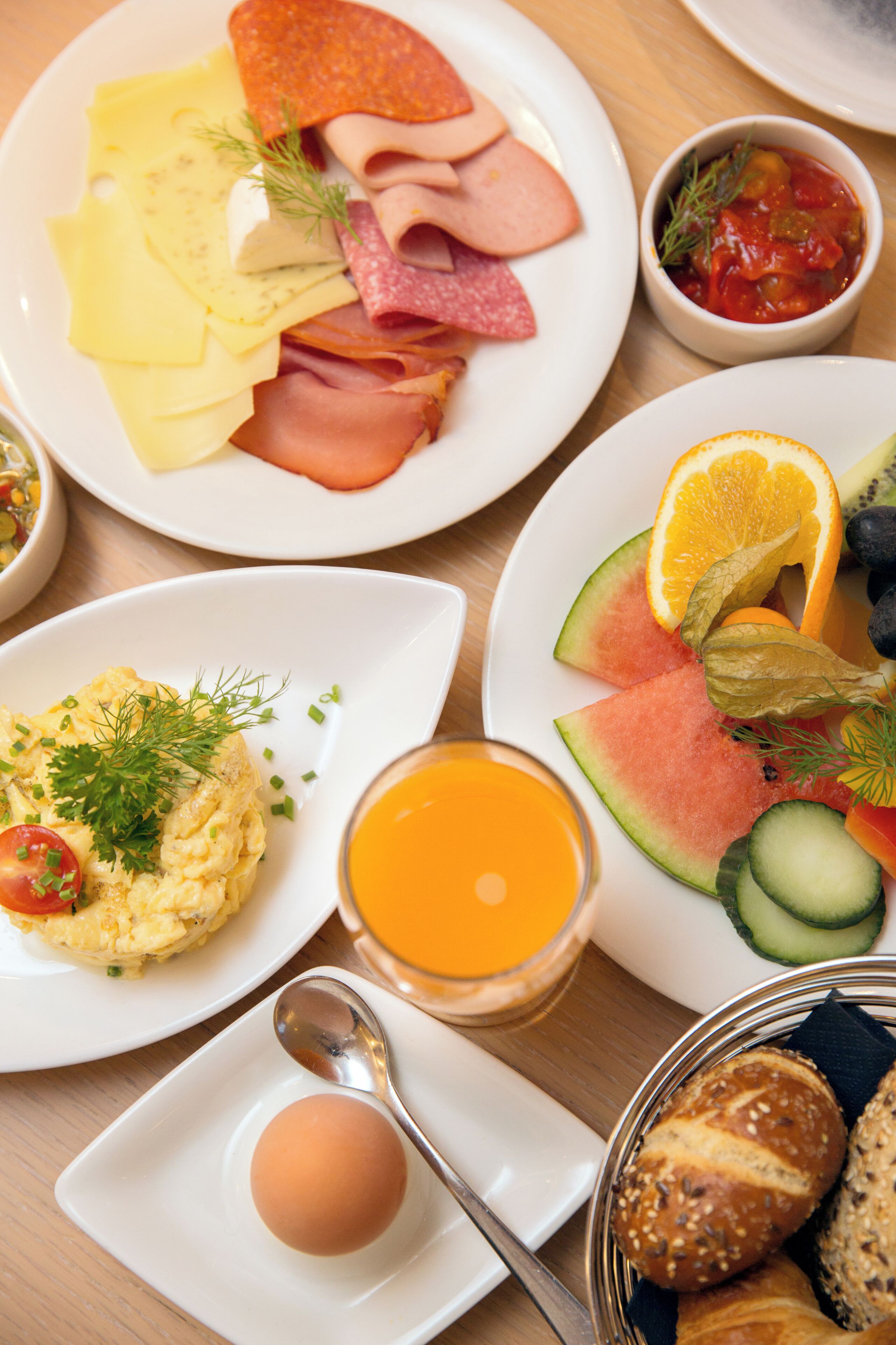 Desayuno con platos de huevos, jamón, queso y pan.