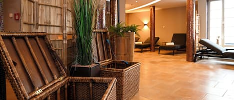 A lobby with wicker furniture, a large plant, and a seating area with chairs and a sofa.