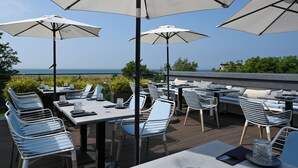 Un área de comedor al aire libre con mesas, sillas y sombrillas, con vistas a un paisaje pintoresco.