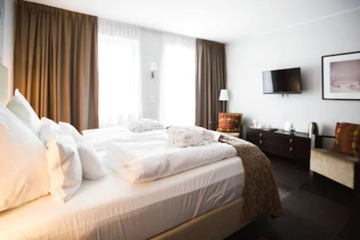 Een hotelkamer met een groot bed, een aan de muur bevestigde televisie, een bureau en een stoel.