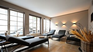 Un cuarto de spa con dos camillas de masaje, una mesita con una planta y un aplique de luz en la pared.