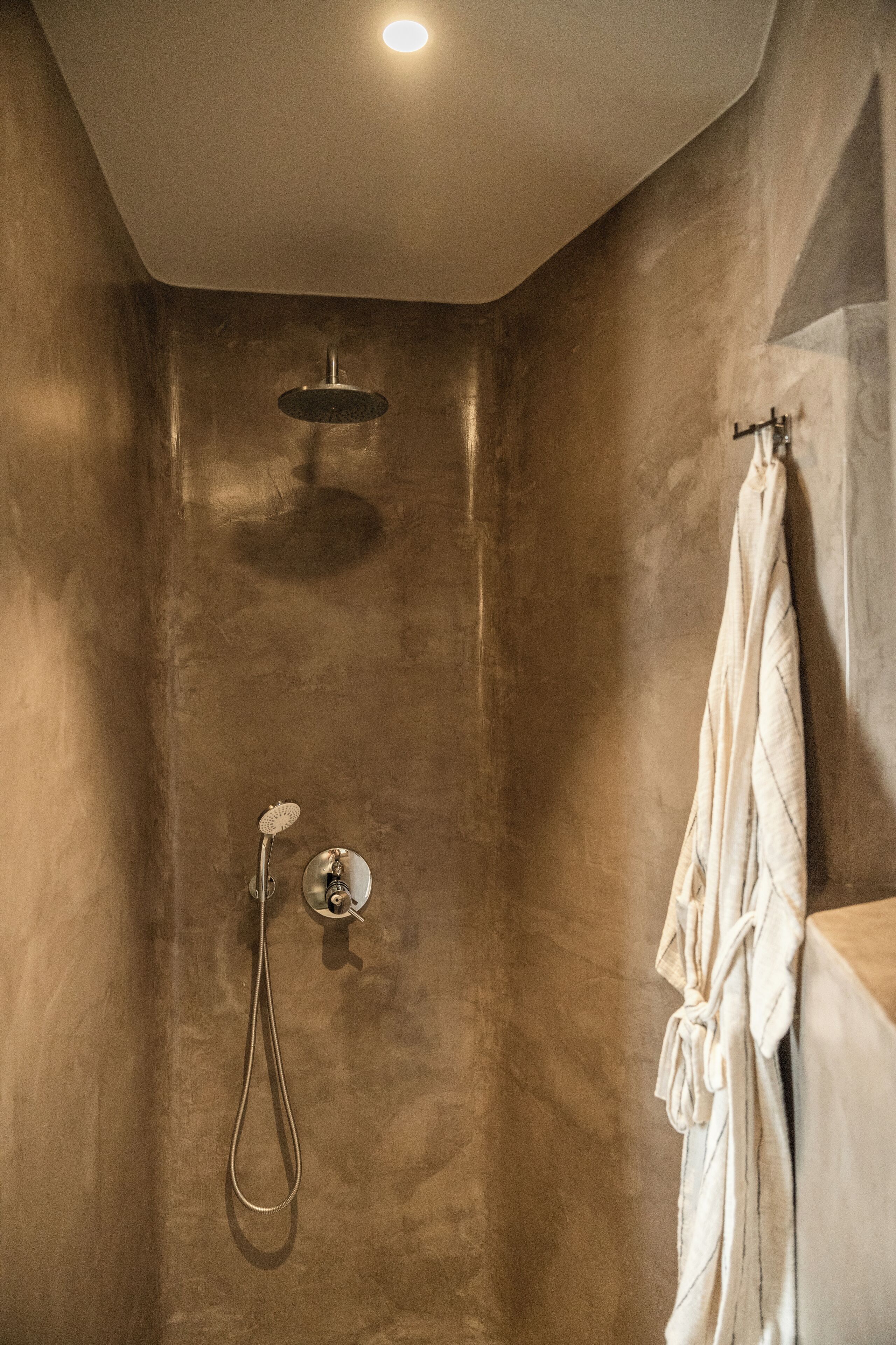 Ein modernes Badezimmer mit Dusche, Handtuchhalter und Deckenleuchte.