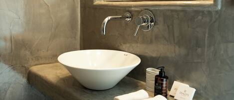 A bathroom with a white basin, a towel, and toiletries on a marble countertop.
