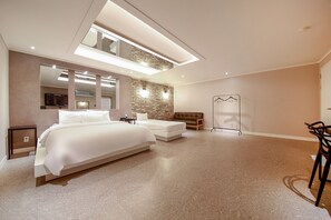 Un dormitorio moderno con una cama grande, una cama más pequeña, un sofá, un espejo, un televisor y un vestidor.