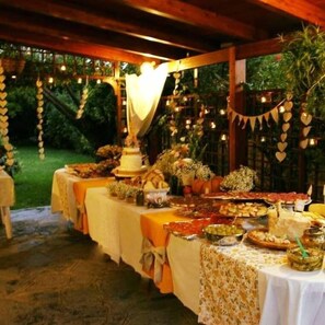 An outdoor dining area with tables set for a meal, surrounded by greenery and string lights. - Podere Il Sorriso Degli Angeli (Serravalle Pistoiese)