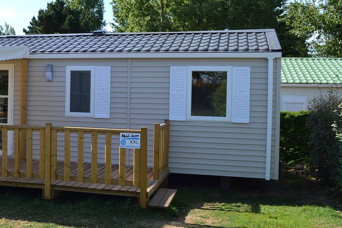 A mobile home with a covered porch and a small deck.