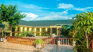 A hotel courtyard with a tiled floor, a wooden fence, and a variety of plants. - Hotel Hilltop Country Club (Kigali)