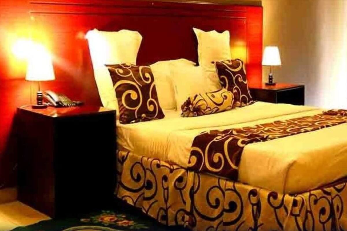 Une chambre d’hôtel avec un grand lit, deux tables de chevet et une tête de lit rouge.