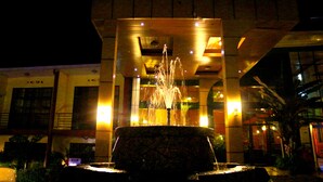 A fountain in front of a building with illuminated windows and a modern architectural design. - Hotel Hilltop Country Club (Kigali)