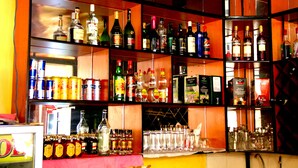 A bar area with shelves stocked with various liquor bottles and canned drinks. - Hotel Hilltop Country Club (Kigali)