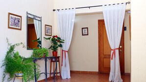 A hallway with a potted plant, a mirror, and a door with a number sign. - Hospedería Ancladero (Mojacar)