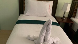 A neatly made bed with a green bedspread and a towel folded in the center. - Adams View Hotel (Moalboal)