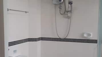 Un baño pequeño y funcional con inodoro, ducha y lavamanos.