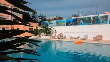 Una piscina al aire libre, sillones reclinables de piscina