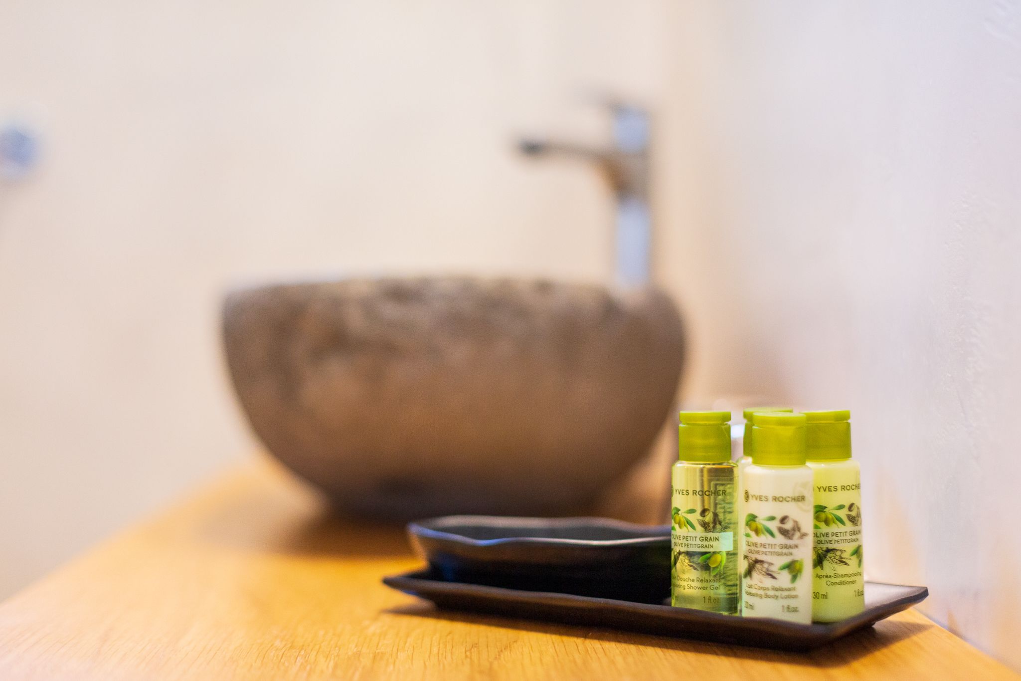 A wooden table with three bottles of Yves Rocher body care products.