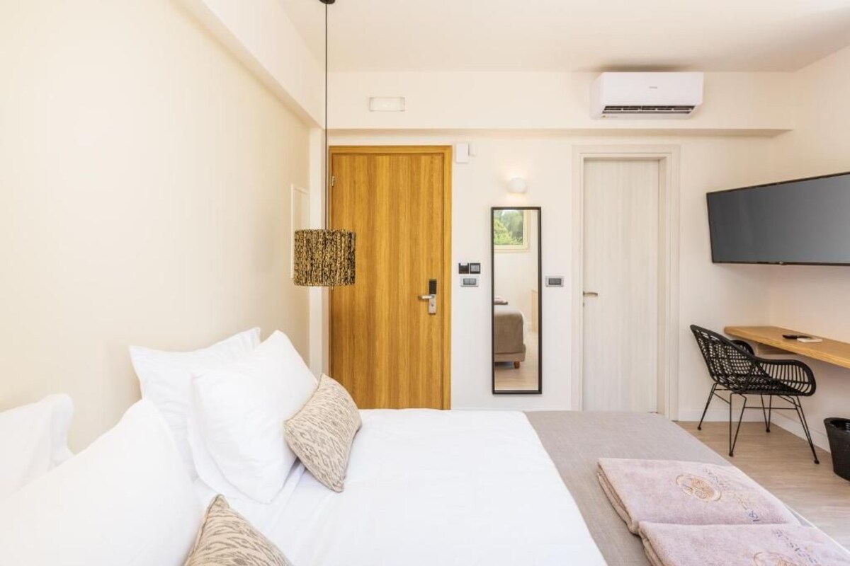 Habitación de hotel con cama, escritorio, silla, televisión y aire acondicionado.