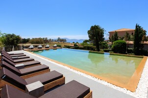 A poolside area with lounge chairs and a clear view of the sea.